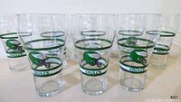 Front view of 8 vintage Coca-Cola Philadelphia Eagles glasses, showing logos and green/white ring accents.