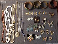 Full lot showing necklaces, bracelets, earrings, brooches, and rings on display surface