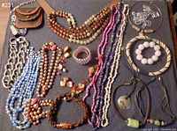 Photo of assorted chunky and choker costume jewelry laid flat on a blue fabric background. Items include multiple bead necklaces, bracelets, keychain coin purse, and pendant necklaces.