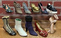 Lot of 11 miniature collectible shoes displayed in two rows on a wooden surface against a brick background. Includes various styles such as floral embroidered, animal prints, sparkly heels, sneakers, boots, and ballet shoe, all detailed miniature replicas.