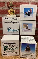 Boxed and unboxed Charming Tails figurines with original and gift store boxes, showing labels and artwork.