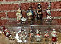 Photo of 10 blown glass Christmas ornaments on display including Santa Claus, snowman, king, and child in snowsuit figurines