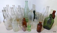 Front and side view of the complete lot of 20 vintage bottles showing variety in color, size, and shape.