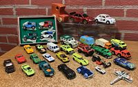 Photo showing all toy cars in the lot arranged on a table including boxed Matchbox set, various colored vehicles, and wooden toy car