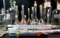 Close-up of assorted volumetric flasks and lab thermometers laid horizontally