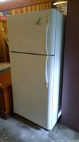 Front view of white upright Frigidaire refrigerator freezer showing freezer on top and fridge below, with vertical handles on right side.