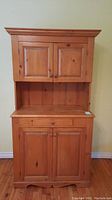 Front view of the solid wood cupboard showing one drawer, lower and upper cabinets with wooden knobs and stained wood finish.