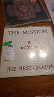 Two vinyl LPs on wood surface: The Mission – The First Chapter and God’s Own Medicine