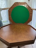 Two men holding the octagonal tabletop showing dining side and game side