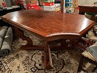 Photo showing solid oak dining table with leaf inserted, detailed top view with beveled edges and wood grain under indoor lighting.