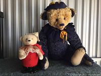 Two mohair teddy bears displayed side by side, showing contrast in size and attire.