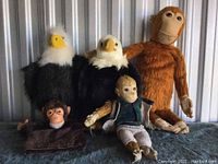 Group photo of two large eagles and two monkey plush toys, showing varying sizes and conditions.
