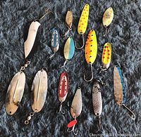 Full layout of 14 assorted vintage fishing lures in various colors and styles on dark textured surface.