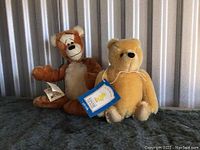 Both plush dolls of Tigger and classic Winnie the Pooh sitting side by side showing jointed limbs and face details.
