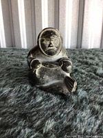 Front view of the carved indigenous figure holding a fish, showing facial details and hand positioning.