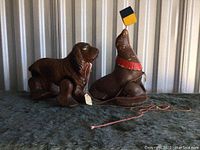Pair of vintage pull toys, dog and circus seal balancing cube, shown on dark fur-like surface.
