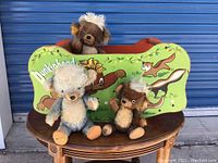 Three plush Punkinhead bears seated in a green painted wooden sleigh/swing decorated with forest motif