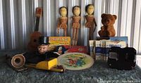Lot overview showing puppet, dolls, carved bear, toy guitar, horn, toy car, game boxes, and children's books