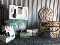 Singer Tiny Serger machine, boxes, and woven basket arranged together