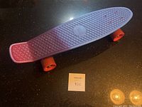 Top view of purple plastic Penny skateboard deck with textured surface and banana shape.