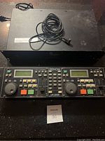 Full front view of Denon DN-2500F dual CD controller showing both jog wheels, LCD screens, multiple buttons and sliders, and power cord.