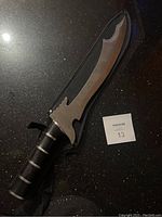 Custom fantasy sword with uniquely shaped blade and wood inlaid handle, shown fully outside of carrying case.