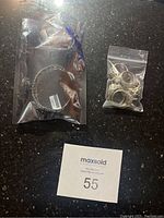 Photo of the bracelet and bag of unset rings laid on a surface with lot number card.