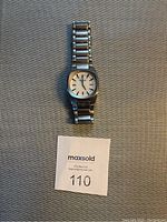 Full view of Nixon silver-toned men's watch showing metal link bracelet and white dial.