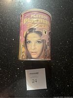 Photo of the front of the cylindrical tin container showing a photographic portrait of Martha Smith with puzzle piece outlines on a pink background.