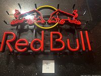 Full view of the Red Bull LED neon sign mounted on metal frame showing the Red Bull text and charging bull logos in red and yellow neon tubing.