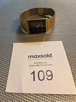 Photo showing the full watch lying on a flat surface with a MaxSold lot number card nearby for reference.