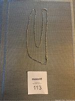 Full length photo of the silver toned chain laid out flat showing the complete necklace.