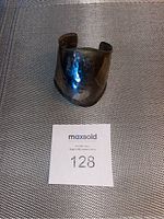 Top view of the sterling silver hammered cuff bracelet showing its curved triangular shape and polished, flattened surface.