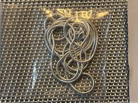 Coiled thin silver toned necklace chain in plastic bag on woven surface.