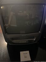 Front view of a small Memorex CRT television with integrated VHS player below the screen, showing the device and part of the surrounding area.