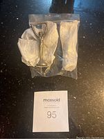 Photo of two vintage metal Canada bottle cap openers wrapped in tissue and plastic bag.