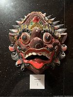 Front view of the painted Indonesian wood mask showing detailed carving and vibrant colors.