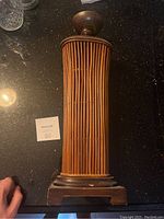 Full view of the tall wooden candle holder showing the vertical bamboo/reed inlay and round candle platform on top with wood base.