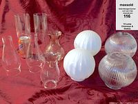 Front view of 10 lamp chimneys and globes showing variety in shapes and styles including frosted and ribbed globes and clear chimneys.