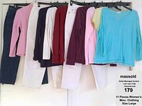 11 pieces of women's clothing hung on hangers including pants and tops in various colors and styles.