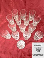 Fifteen clear tall water tumblers arranged on red fabric showing the starburst pattern on base and sides.