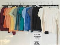 17 women's jerseys and blouses hanging on a rack, assorted colors including dark red, orange, yellow, teal, blue, gray, black, and white.
