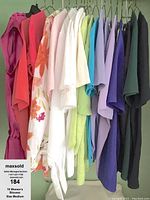Blouses hanging on a rack, showing various colors from pinks, floral, white, greens, blues, purple to black.
