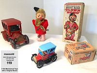 Lot of three vintage mechanical toys displayed with two original boxes. Includes red car missing a fender, blue and red car, and Clown 'Hobo' mechanical toy with cymbals.