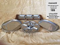Four stainless steel serving pieces shown together on patterned background: three-section rectangular tray in teak wood, round divided tray, and two oval trays.