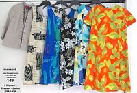 Photo showing five dresses and one jacket hanging on a rack, from left to right: light beige jacket, beige abstract print dress, blue-green abstract pattern dress, black floral print dress, blue and white floral print dress, orange yellow floral dress.