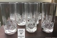 Set of 8 tall clear crystal water tumblers displayed in a row, showing their tall shape and cut-look pattern at the base.