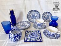 Lot of blue and white china featuring Queen Elizabeth 1977 Silver Jubilee designs, multiple blue glass pitchers and bottles, a blue and white ceramic candle holder, and a decorative tile.