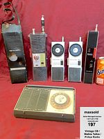 Front view of six radios: Realistic handheld CB radio with case, two Motorola walkie-talkies, two Sony walkie-talkies, and a vintage beige police radio with dial and speaker grill. Soda can is for size comparison only.