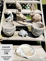 Lot of 7 garden ornaments displayed on wooden outdoor stairs, showing gnome, duck, bunny, turtle, cat bowl, and two urn planters in sunlight.